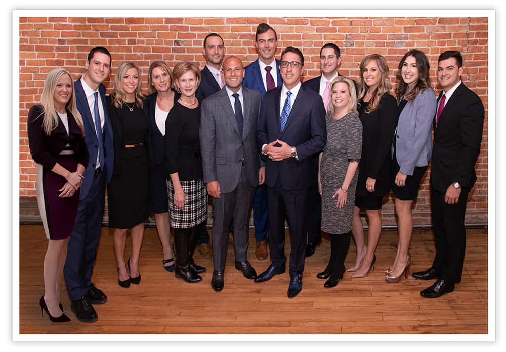 Group photo of The Abood Law Firm standing in front of brick wall.